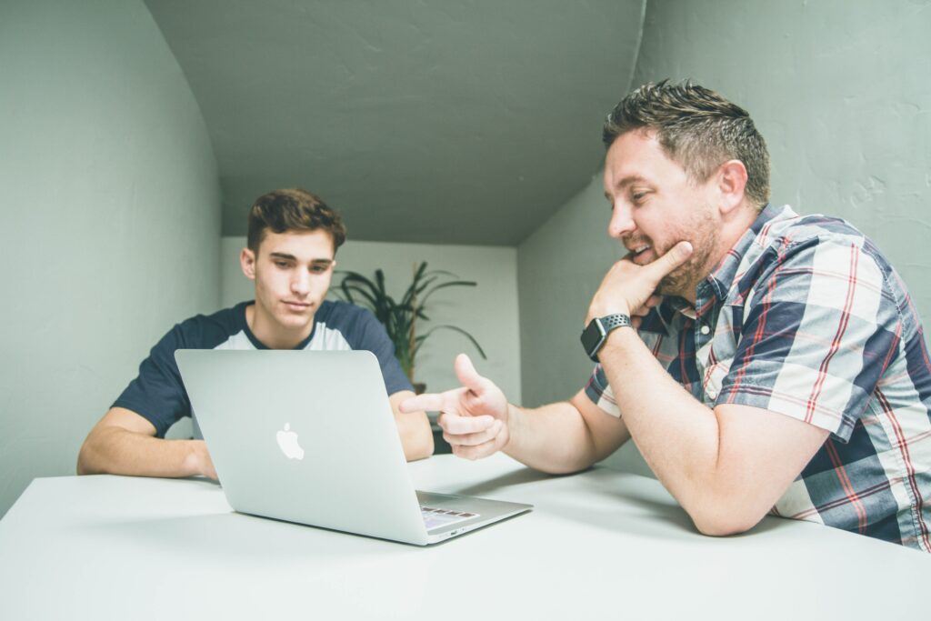 Tutor guiding a secondary school student through exam preparation. Secondary school student completing written exam practice
